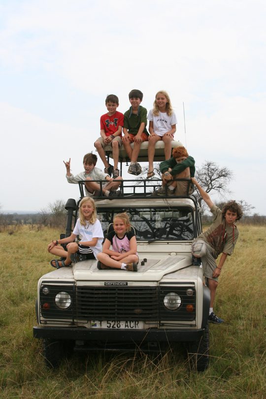 kids on a family safari sitting on a Land Rover