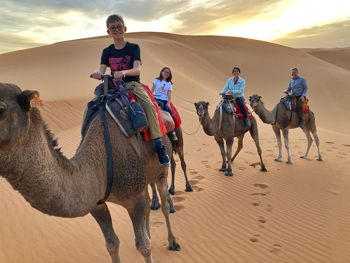 family riding camels in morocco